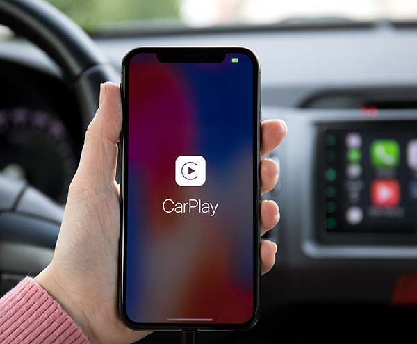 Hand holding smartphone (with CarPlay app) in car