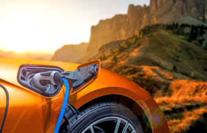 Image of electric car charging in front of mountain landscape.